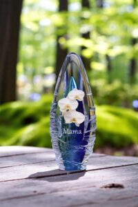 een blauwe glazen urn met een afbeelding van een witte orchidee en een naam in zilver sign folie