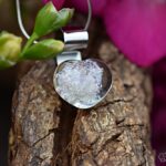 Glazen hartje met crematie-as, handgemaakt gedenksieraad met glinsterend meerkleurig glas aan een zilverkleurige hanger. • Glass heart pendant with cremation ashes, handmade memorial jewellery with sparkling multicoloured glass and a silver-coloured bail. • Herzanhänger aus Glas mit Asche, handgefertigtes Andenken mit schimmerndem, mehrfarbigem Glas und silberfarbener Öse.