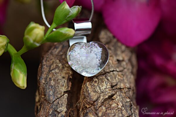Glazen hartje met crematie-as, handgemaakt gedenksieraad met glinsterend meerkleurig glas aan een zilverkleurige hanger. • Glass heart pendant with cremation ashes, handmade memorial jewellery with sparkling multicoloured glass and a silver-coloured bail. • Herzanhänger aus Glas mit Asche, handgefertigtes Andenken mit schimmerndem, mehrfarbigem Glas und silberfarbener Öse.