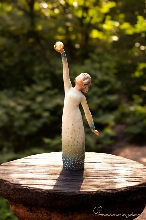Willow Tree stijlbeeldje – meisje in jurk met gouden en blauwe details reikt met haar hand naar de hemel en houdt een mini-urn vast