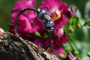 een dames bangle gedenkarmband met een dubbele crematie-as verwerking in glazen bedels