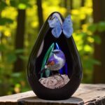 Design urn van glas met vogeltje in fotofolie en vlinder van tule, herdenkingsurn voor crematie-as.