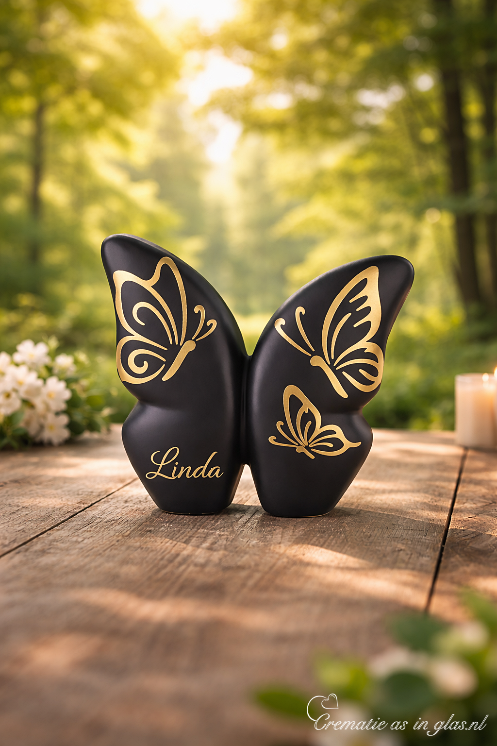 Black ceramic butterfly urn on wooden table in forest, with gold foil butterflies and space for name, suitable for cremation ashes.