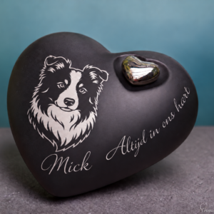 Matzwarte keramische harturn met zilverkleurig bordercollieportret, de voorbeeldnaam Mick, het opschrift ‘Altijd in ons hart’ en een metalen hartje.