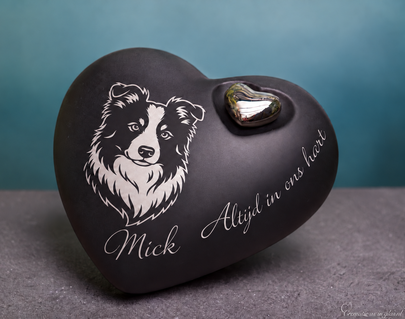 Matzwarte keramische harturn met zilverkleurig bordercollieportret, de voorbeeldnaam Mick, het opschrift ‘Altijd in ons hart’ en een metalen hartje.